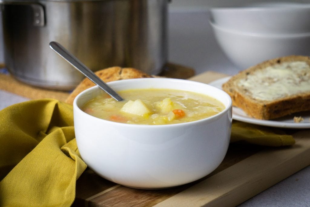 Scottish Potato Soup and Tattie Soup Recipe in a bowl with bread and potatoes beside