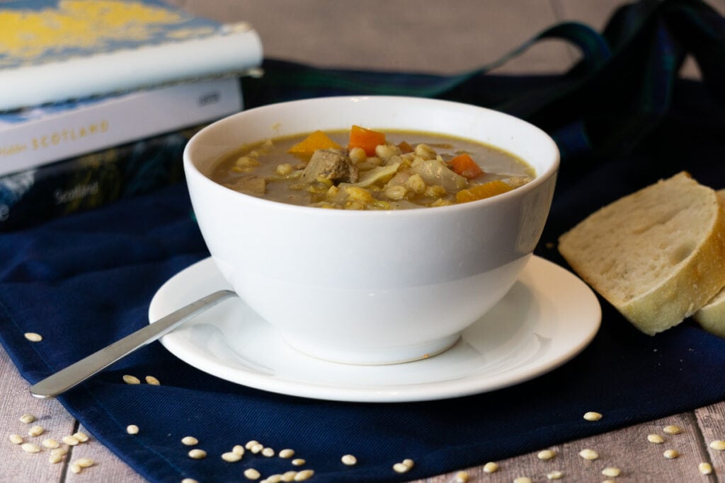 Scotch Broth Recipe in a bowl with bread and books nearby