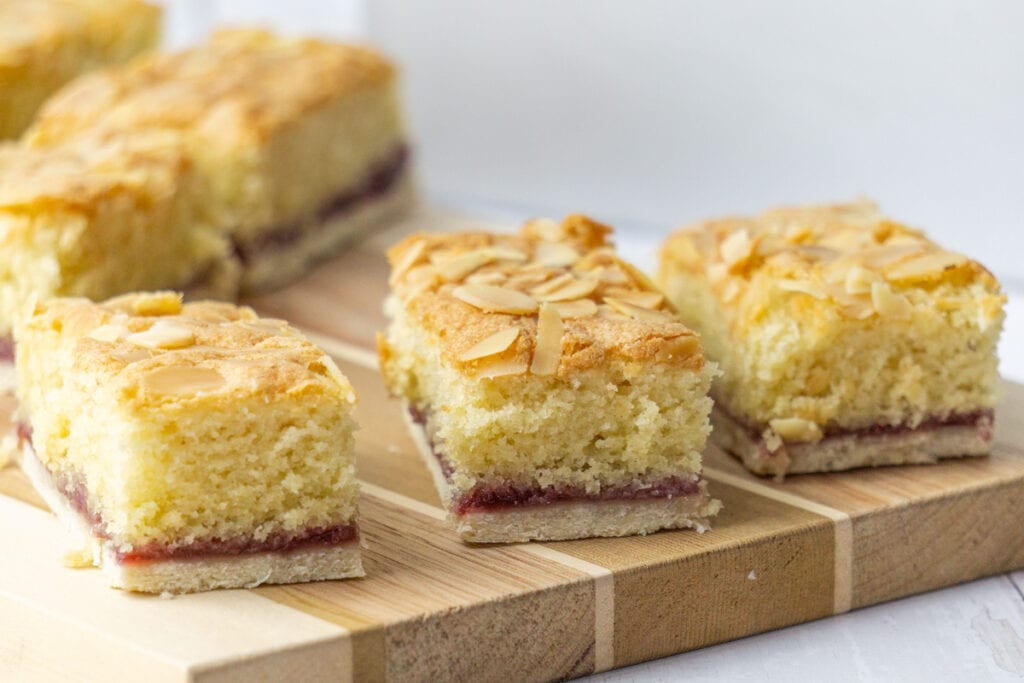 Almond Slice Recipe on a wooden board - A Bakewell Slice with pastry bottom, raspberry jam, and an almond sponge
